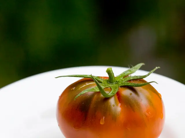 In this image we can see a tomato on a white surface which looks like a plate and in the...