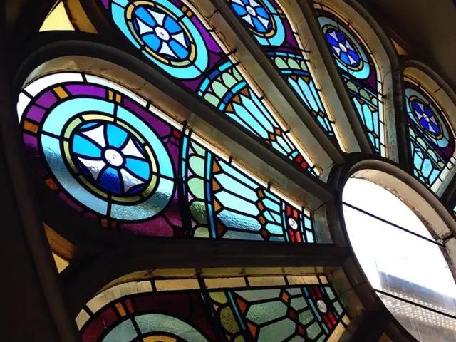 In this image there is a glass window having few paintings on it. Window is in flower structure.